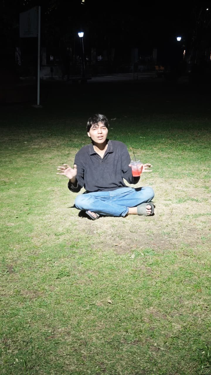 Chaitanya sitting cross-legged on a grass field